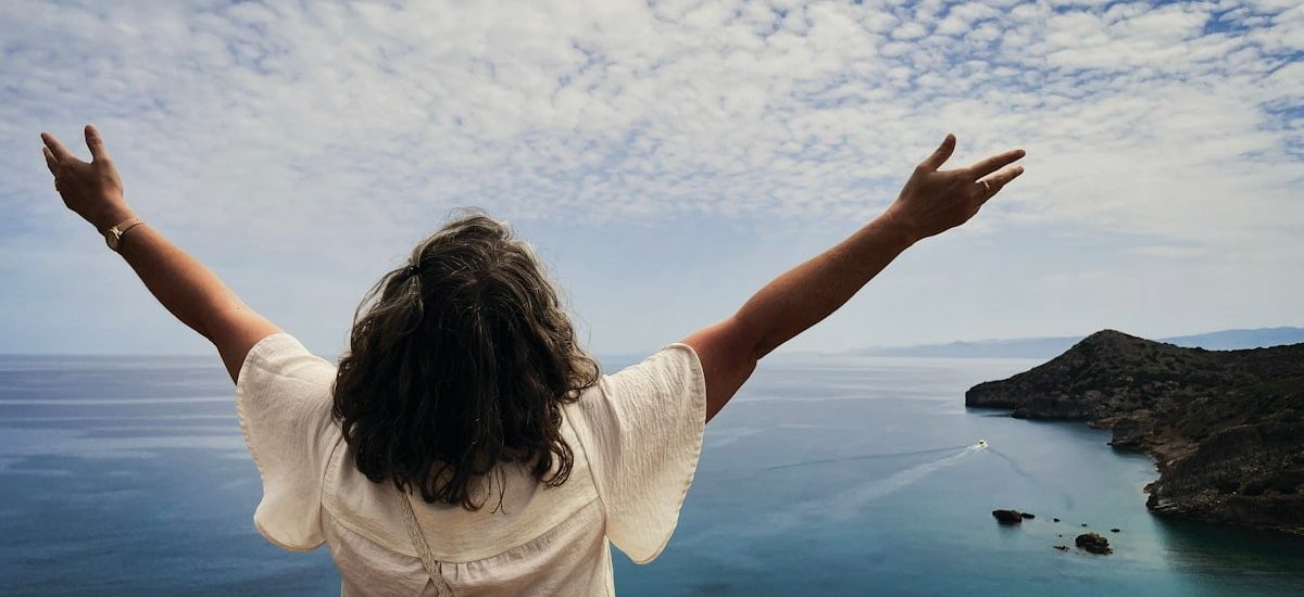Woman with arms outstretched overlooking the ocean.