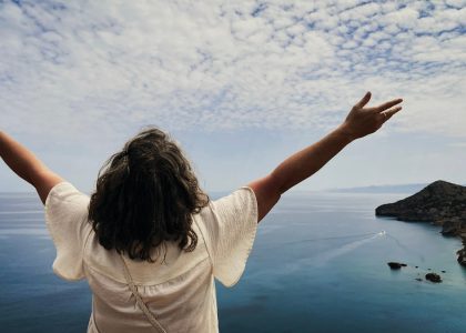 Woman with arms outstretched overlooking the ocean.