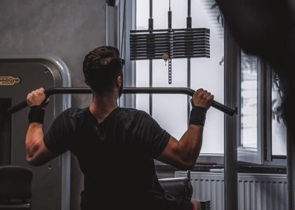 Back view of a man exercising with lat pulldown machine in the gym.